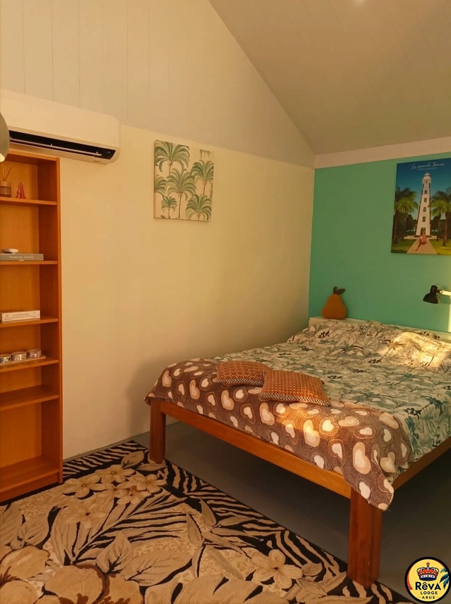 Chambre avec lit double, mur turquoise et tapis aux motifs polynésiens
